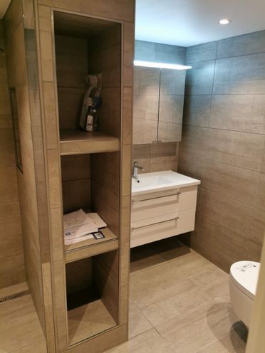 Renovert baderom med innebygget oppbevaring og vaskeservant med speil