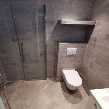 Renovert baderom med vegghengt toalett og flis i betongutførelse
