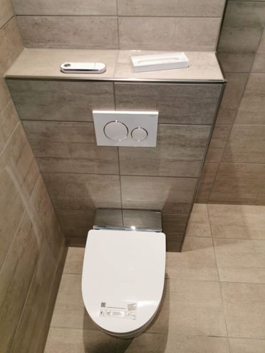 Nytt vegghengt toalett i renovert fliskledd baderom