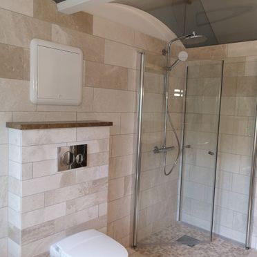 Renovert baderom med fliskledd dusjhjørne og vegghengt toalett