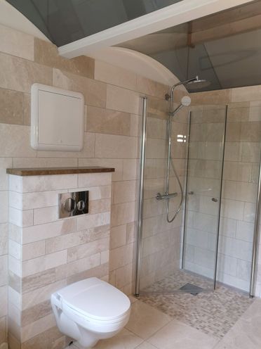 Renovert baderom med fliskledd dusjhjørne og vegghengt toalett