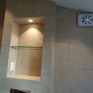Detaljbilde av glasshylle innebygd i fliskledd baderomsvegg