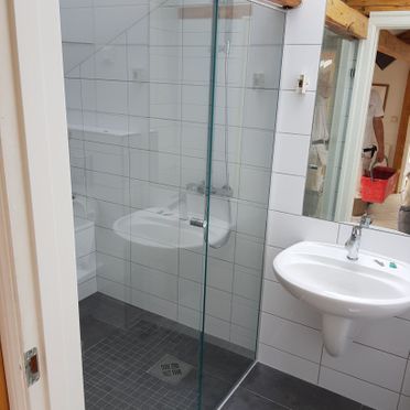 Renovert baderom med vask, speil og stor dusjsone med glassdør