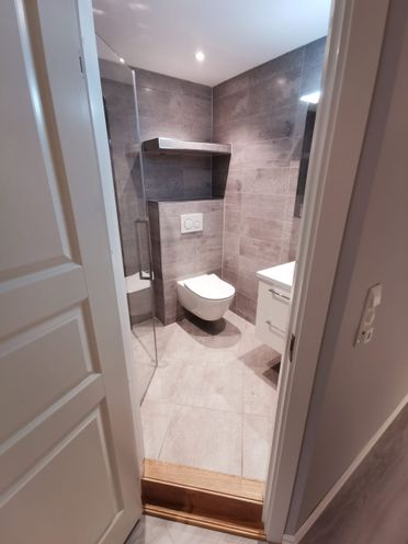 Renovert baderom med betongflis og vegghengt toalett sett utenfra