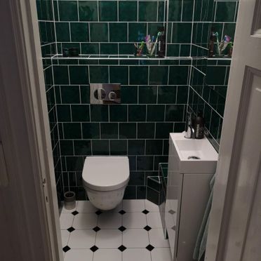 Toalett med smaragdgrønne veggfliser og liten servant
